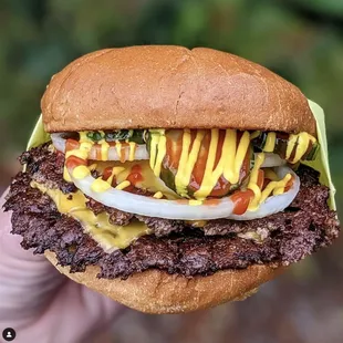 a hand holding a hamburger with ketchup and mustard