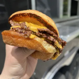 a hand holding a cheeseburger