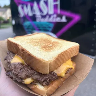 a hand holding a grilled cheeseburger