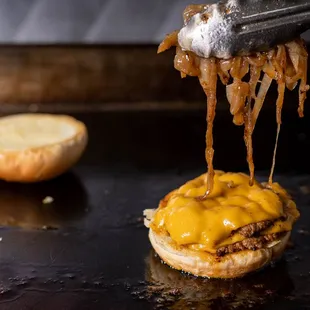 a cheeseburger being drizzled with melted cheese