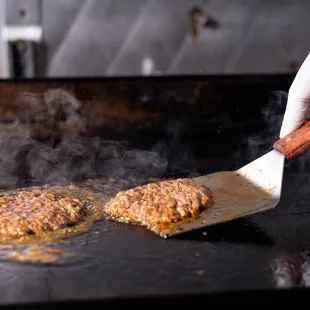 a person cooking burgers on a grill