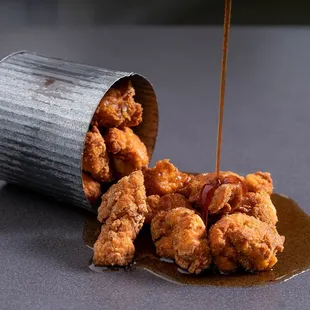 fried chicken being drizzled with sauce