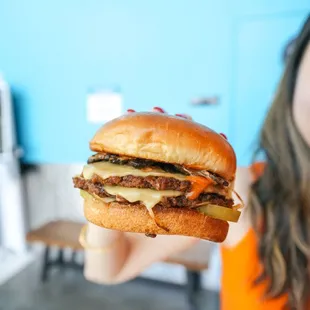 a woman holding up a cheeseburger