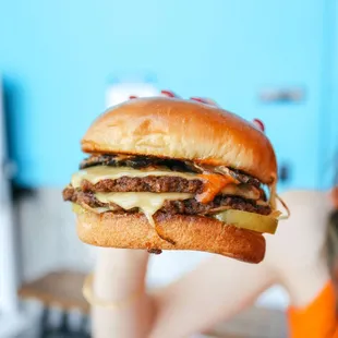 a woman holding up a cheeseburger