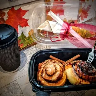 a container of cinnamon rolls and a cup of coffee