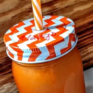 a jar of orange juice with a straw