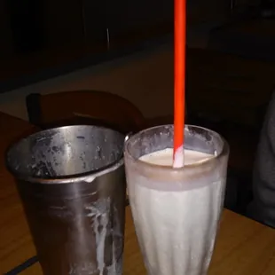 a glass of milkshake and a metal cup