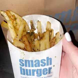 a person holding a paper cup of fries