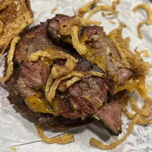 a grilled steak sandwich with onion rings