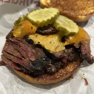 a beef sandwich with pickles and cheese