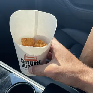 a hand holding a paper cup of food