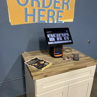 a tablet on a counter with a sign that says order here