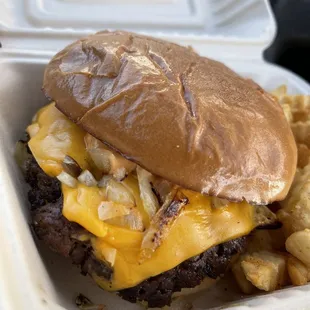 a burger and fries in a styrofoam container