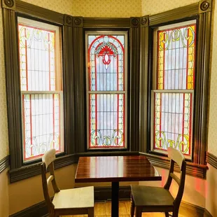 a table and chairs in front of stained glass windows