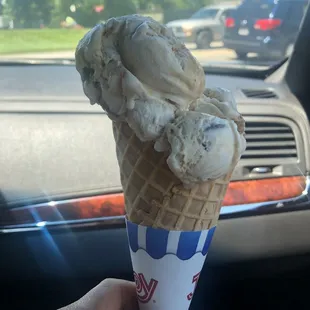 a hand holding a cone of ice cream