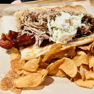 a pulled pork sandwich with cole slaw and potato chips
