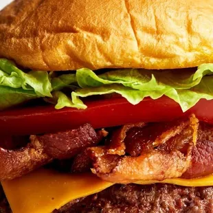 a burger with bacon, lettuce, tomato, and cheese