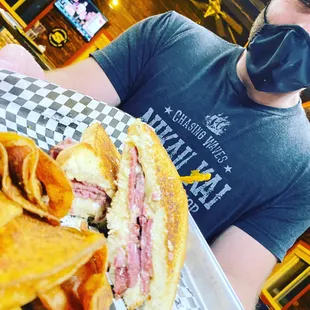 a man wearing a face mask and holding a sandwich