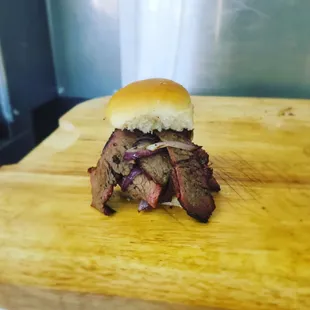 a beef sandwich on a wooden cutting board