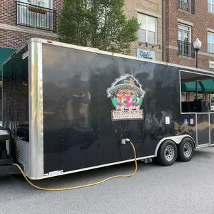 a black food truck parked in front of a brick building