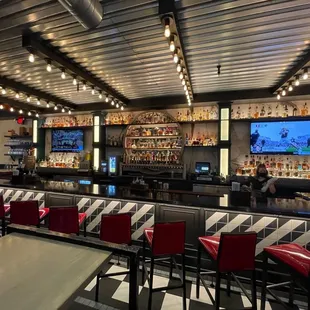a view of a bar with red chairs