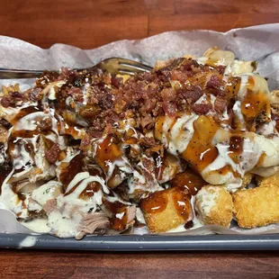 Pig Taters - tater tots with pulled pork and pepper Jack cheese with spicy sauce. Best I&apos;ve ever had.