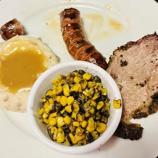 A spoon of boxed mashed potatoes and canned gravy, burnt bland corn.
