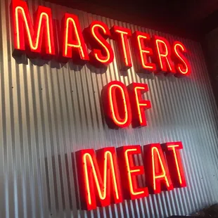 a neon sign that says masters of meat