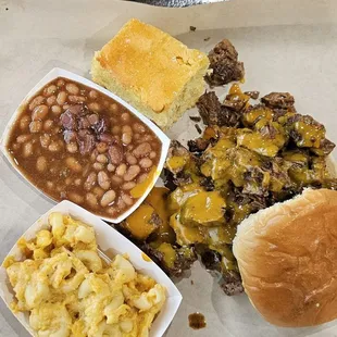 Smoked brisket sandwich with cornbread, baked beans, and mac N cheese