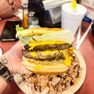 a hand holding a cheeseburger