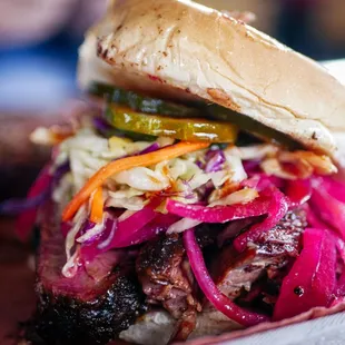 a pulled pork sandwich with coleslaw and pickles