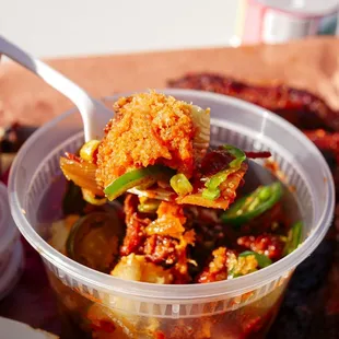 a hand holding a spoon full of food