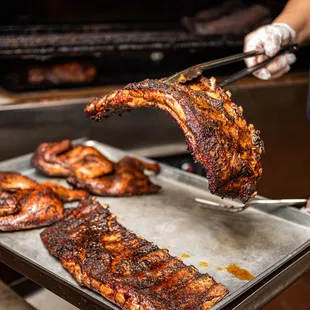 a man holding a spatula over a rack of ribs