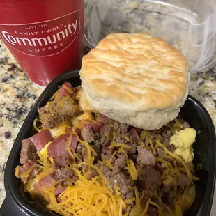 Brisket and sausage breakfast bowl with potatoes and cheese and a homemade biscuit