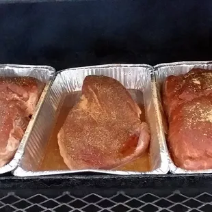 three meats cooking in foil pans