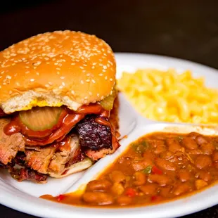 a pulled pork sandwich with beans and macaroni and cheese