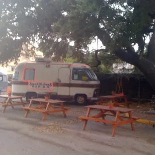 ows an ice cream van parked next to picnic tables