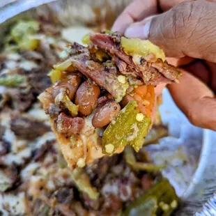 ws a hand holding a piece of pizza