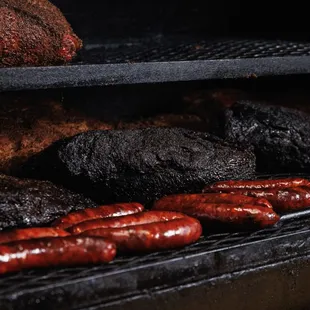 ws a variety of sausages cooking on a grill