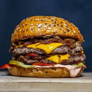 a hamburger with cheese, onions, peppers, and other toppings