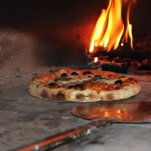  pizza being cooked in a brick oven