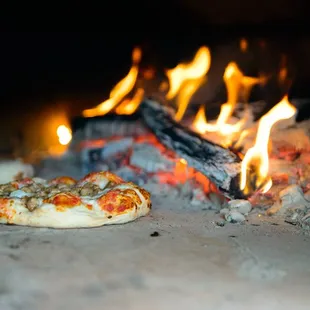  pizza cooking in front of a fire