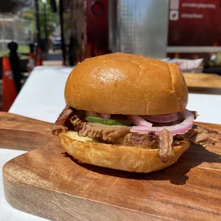 a pulled pork sandwich on a wooden cutting board