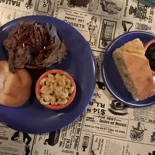 Brisket sandwich with Mac n cheese, greens, and cornbread.