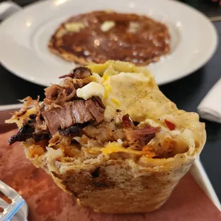 Breakfast burrito with brisket, sweet potato pancake in the background