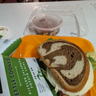 Marble rye sandwich with chips and side dish.
