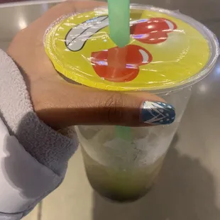 a hand holding a plastic cup with a straw and a green straw