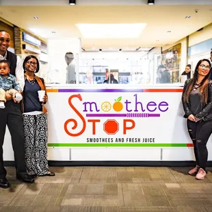 a group of people standing in front of a smoothee stop sign