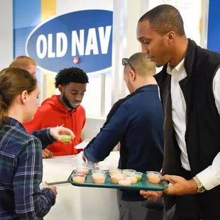 a man serving a tray of cupcakes