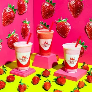 strawberries and smoothie cups with strawberries in the background